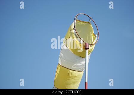Weiß - gelbe Windsocke auf der Stange auf dem blauen Himmel Hintergrund mit Kopierraum aufgenommen. Stockfoto