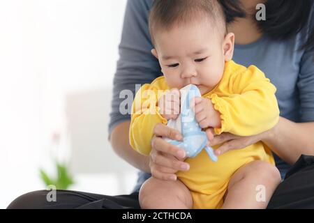 Liebevolle Mutter Schuhe auf Baby auf Sofa zu Hause Stockfoto