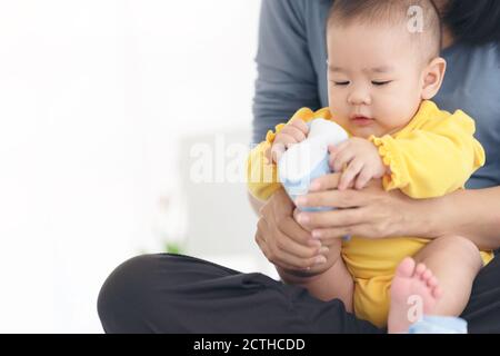 Liebevolle Mutter Schuhe auf Baby auf Sofa zu Hause Stockfoto