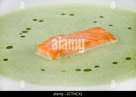 Grüne Spinatpüree-Suppe mit Lachsscheiben. Nahaufnahme auf einem weißen Teller. Stockfoto