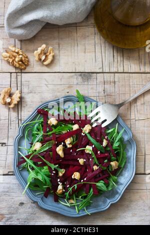 Vitaminsalat aus rohen Rüben, Rucola, Walnüssen und Olivenöl auf einem Holztisch. Rustikaler Stil. Stockfoto