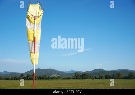 Weiß - gelbe Windsocke auf der Stange auf dem blauen Himmel Hintergrund mit Kopierraum aufgenommen. Stockfoto