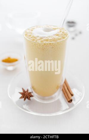 Ein Glas Curcuma Latte mit Glasrohr auf weiß Nahaufnahme des Tisches Stockfoto