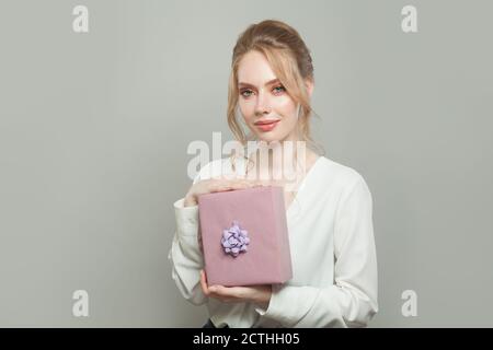Hübsche junge Frau hält rosa Geschenk auf weißem Hintergrund Stockfoto
