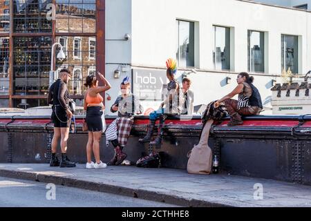 Eine Gruppe von Punks, die an einem ungewöhnlich warmen späten Septembernachmittag auf der Brücke über den Regent's Canal in Camden Lock um Biergeld wirbt, London, Großbritannien Stockfoto