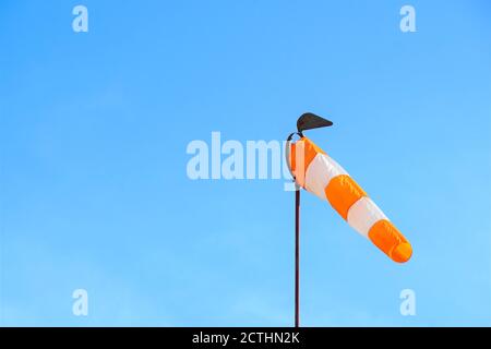 Weiß - gelbe Windsocke auf der Stange auf dem blauen Himmel Hintergrund mit Kopierraum aufgenommen. Stockfoto