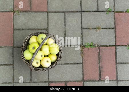 Ein kleiner Korb mit grünen und gelben Äpfeln. Rustikaler Stil. Horizontale Ausrichtung. Draufsicht. Speicherplatz kopieren. Stockfoto