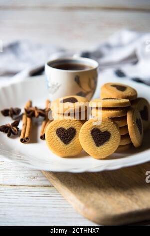 Kekse und schwarzer Kaffee auf einem weißen Teller auf einem Hintergrund Stockfoto