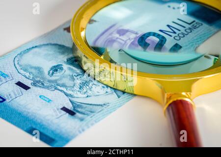 Costa Rica Geld. Banknote von Two Thousand Colones mit einer Lupe darauf. Das Konzept der Betrachtung der wirtschaftlichen Situation des Landes und Stockfoto