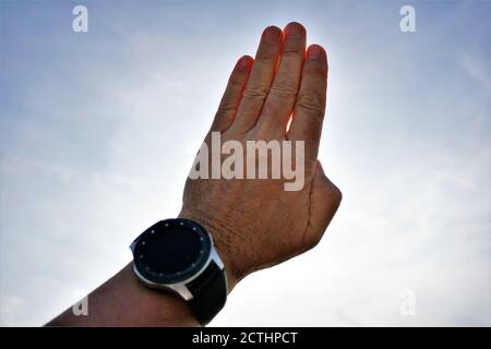 Einfaches Konzept der Hand eines Mannes mit Smartwatch und Sonnenstrahlen durch seine Finger. Stockfoto