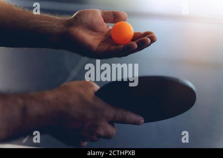 Ein junger Mann spielt Tischtennis. Er hält einen Ball und einen Schläger in den Händen Stockfoto