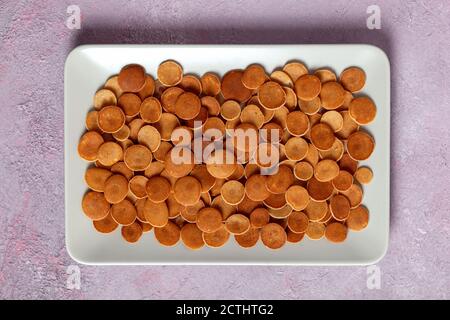 Trendiges, hausgemachtes Frühstück, Pfannkuchen, Müsli, Mini-Pfannkuchen auf hellem Teller auf rosa Betongrund Stockfoto
