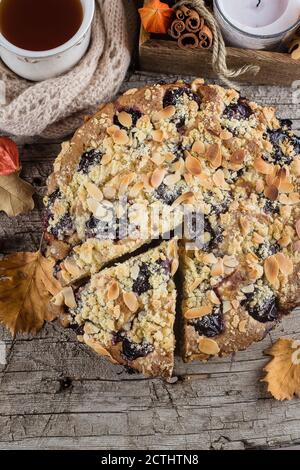 Gemütliches Herbstessen. Hausgemachter Herbstkuchen mit Nüssen und Pflaumen auf Holzhintergrund, Draufsicht, Kopierraum. Stockfoto