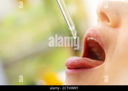 Frau nimmt Vitamintropfen im Mund von Tropf. Kopieren Raum Stockfoto