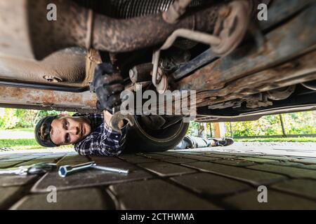 Mann repariert Boden von rostigen alten Auto. Mechaniker arbeiten Stockfoto