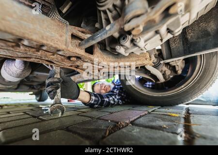 Mann Reparatur Auto. Mechaniker Inspektion Aufhängung System unter dem Fahrzeug zu Hause Garage Stockfoto