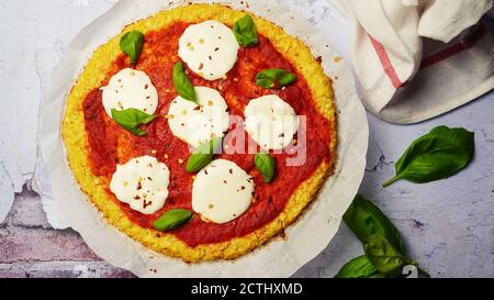 Hausgemachte Blumenkohl Kruste Pizza mit frischen Basilikumblättern gekrönt Stockfoto