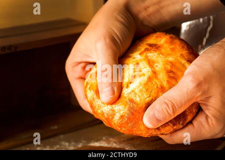 Ein orientalisches Fladenbrot, gefüllt mit Fleisch in den Händen eines Mannes. Pita gefüllt mit Fleisch in den Händen eines Mannes. Die Hände des Kochs brechen die indische na Stockfoto