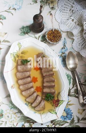 Aspic der Zunge verziert mit gekochten Karotten und Petersilie auf einem festlichen Hintergrund. Rustikaler Stil. Stockfoto