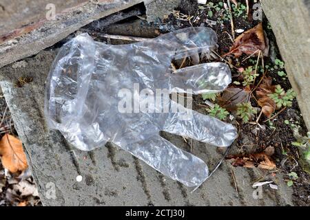 Weggeworfene Einweg-Plastikhandschuhe als Abfall auf dem Bürgersteig Stockfoto