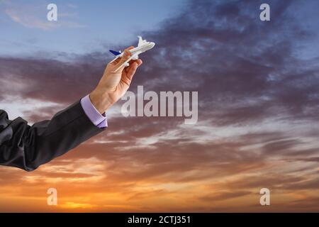 Nahaufnahme Foto von der Hand des Menschen holding Spielzeug Flugzeug gegen den blauen Himmel mit Wolken Stockfoto
