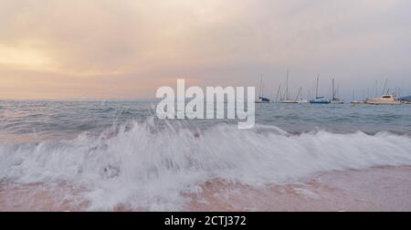 Bei Sonnenuntergang brechen die Wellen am Strand vor Booten, italienische Landschaft Stockfoto