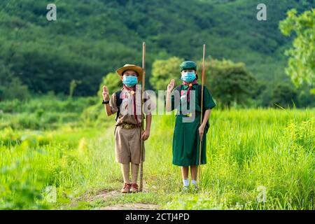 Asian Scout trägt eine Maske und zeigen Scout Symbol, neue normale Stockfoto