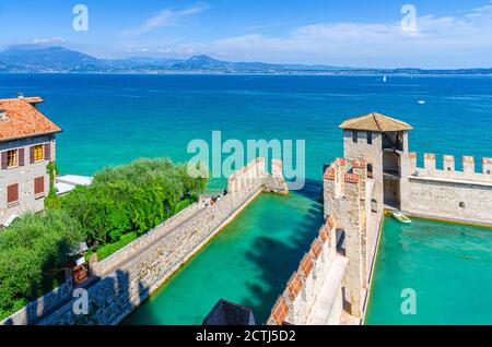 Sirmione, Italien, 11. September 2019: Kleiner befestigter Hafen mit türkisfarbenem Wasser, Scaligero Burg Castello Festung, Stadt am Gardasee, mittelalterliche Burg mit Steintürmen und Backsteinmauern, Lombardei Stockfoto