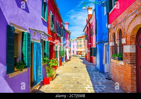 Burano Insel schmale gepflasterte Straße zwischen bunten Häusern Gebäude mit bunten hellen Wänden, blauer Himmel sonnigen Sommertag, Provinz Venedig, Region Venetien, Norditalien. Burano Postkarte Stockfoto