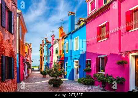 Burano Insel schmale gepflasterte Straße zwischen bunten Häusern Gebäude mit bunten hellen Wänden, blauer Himmel sonnigen Sommertag, Provinz Venedig, Region Venetien, Norditalien. Burano Postkarte Stockfoto