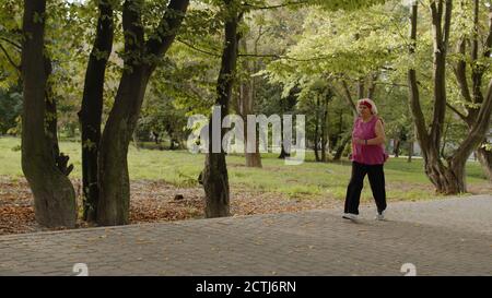 Ältere alte Frau läuft im Stadtpark und mit Smart Watch, genießen einen gesunden aktiven Lebensstil. Ältere weibliche Läuferin trainieren Cardio-Morgen-Übung im Freien. Aktive Sportler Stockfoto