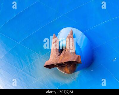 Ein riesiger rostiger Anker hängt draußen auf einem blauen Schiff Stockfoto