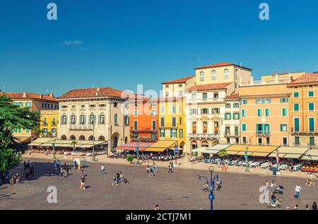 Verona, Italien, 12. September 2019: Piazza Bra Platz im historischen Stadtzentrum mit Reihe von alten bunten bunten Gebäuden Cafés und Restaurants, grüne Bäume und Wandertouristen, blauer Himmel Stockfoto