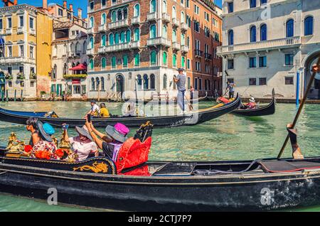 Venedig, Italien, 13. September 2019: Gondoliere und Touristen auf Gondel traditionelle Boot Segeln auf dem Wasser des Canal Grande Wasserstraße mit venezianischer Architektur typischen bunten Gebäuden Hintergrund Stockfoto