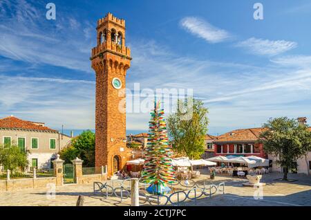 Murano, Italien, 14. September 2019: Murano Uhrenturm Torre dell'Orologio von San Stefano Kirche und bunten weihnachtsbaum aus Murano-Glas auf Campo Santo Stefano Platz in Murano-Inseln Stockfoto