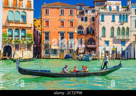 Venedig, Italien, 13. September 2019: Gondoliere und Touristen auf Gondel traditionelle Boot Segeln auf dem Wasser des Canal Grande Wasserstraße mit venezianischer Architektur typischen bunten Gebäuden Hintergrund Stockfoto