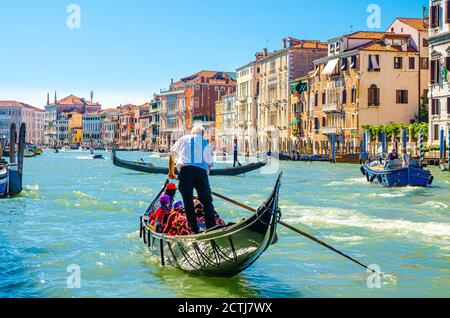 Venedig, Italien, 13. September 2019: Gondoliere und Touristen auf Gondel traditionelle Boot Segeln auf dem Wasser des Canal Grande Wasserstraße mit venezianischer Architektur typischen bunten Gebäuden Hintergrund Stockfoto