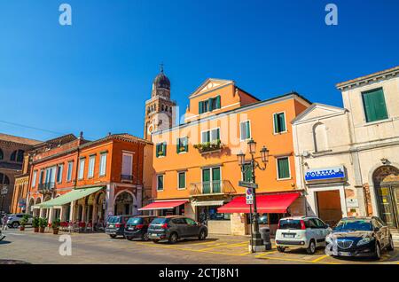 Chioggia, Italien, 16. September 2019: Uhr und Glockenturm der Kathedrale Santa Maria Assunta und Reihe von bunten bunten Gebäuden in der Altstadt, blauer Himmel im Sommer, Region Venetien Stockfoto