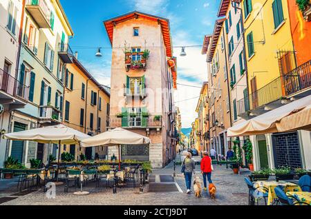 Brescia, Italien, 11. September 2019: Traditionelles buntes Gebäude mit Balkonen in typisch italienischer Straße, Tische und Zelt von Straßenrestaurant, Frauen mit Hunden, historisches Stadtzentrum, Lombardei Stockfoto