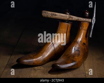 Ein Paar klassischer Schuster aus Holz und traditionelle Schuster Hammer dramatisch beleuchtet auf Holzbrettern Stockfoto