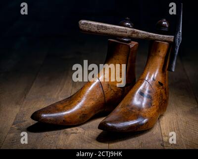 Ein Paar klassischer Schuster aus Holz und traditionelle Schuster Hammer dramatisch beleuchtet auf Holzbrettern Stockfoto