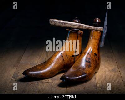 Ein Paar klassischer Schuster aus Holz und traditionelle Schuster Hammer dramatisch beleuchtet auf Holzbrettern Stockfoto