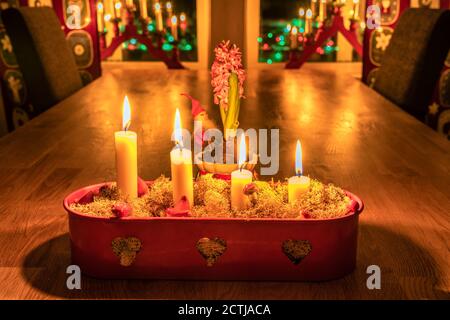 Vier brennende Adventskerzen in rotem Kerzenständer auf Eichentisch. Heiligabend. Traditionelle Dekoration in schwedischem Haus mit Fensterbeleuchtung, Hyazinthe Flowe Stockfoto