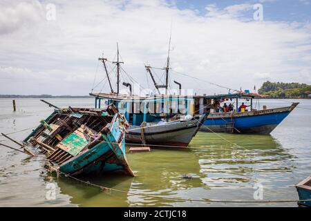 Ein halb eingetauchtes Fischerboot und zwei weitere Holzboote im Pukat Village, einem Fischerdorf an der Jalan Bokara im Süden von Sandakan. Stockfoto