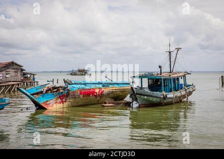 Ein halb eingetauchtes Fischerboot und ein weiteres Holzboot im Pukat Village, einem Fischerdorf an der Jalan Bokara im Süden von Sandakan. Stockfoto