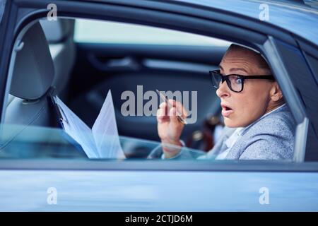 Autounfall. Schockiert und verängstigt Geschäftsfrau Blick aus einem Autofenster mit Mund geöffnet, während auf dem Rücksitz im Auto sitzen und Stockfoto