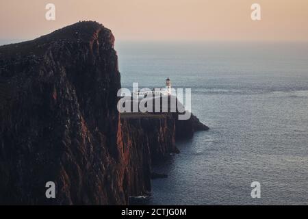 Eine Schminkerei eines feinen Leuchtturms, der auf einer atemberaubenden Klippe steht, die von der untergehenden Sonne beleuchtet wird. Neist Point, Isle of Skye, Schottland Stockfoto