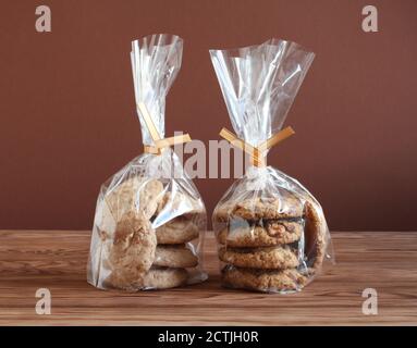 Haferflocken mit Walnüssen und Rosinen und Mandelgebäck in transparenten Tüten auf einem Holztisch. Nahaufnahme Stockfoto