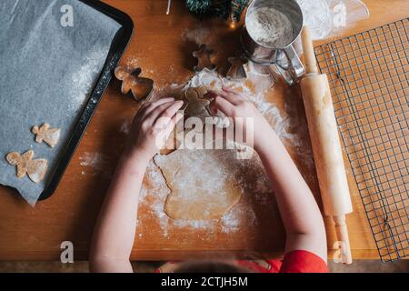 Overhead-Ansicht eines Mädchens mit einem Ausstecher zu Machen Lebkuchen Mann Stockfoto