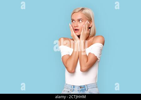 Freistil. Junge blonde Frau in oben isoliert auf blau halten Gesicht Mund geöffnet geschockt Stockfoto